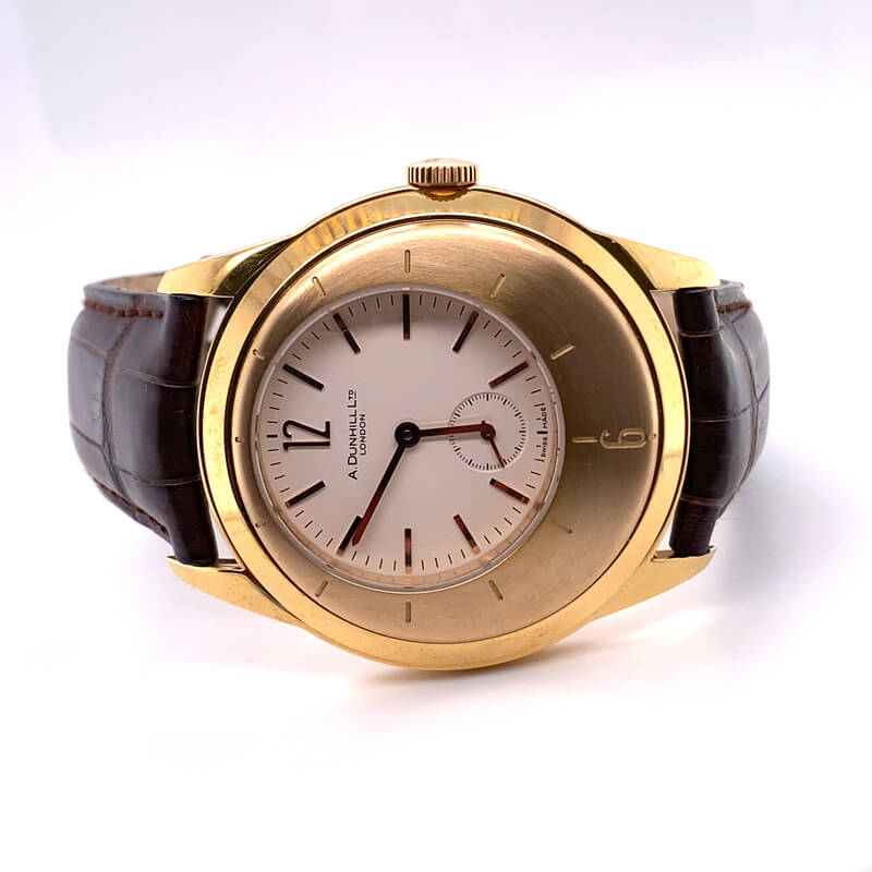 a gold watch with brown leather straps on a white surface