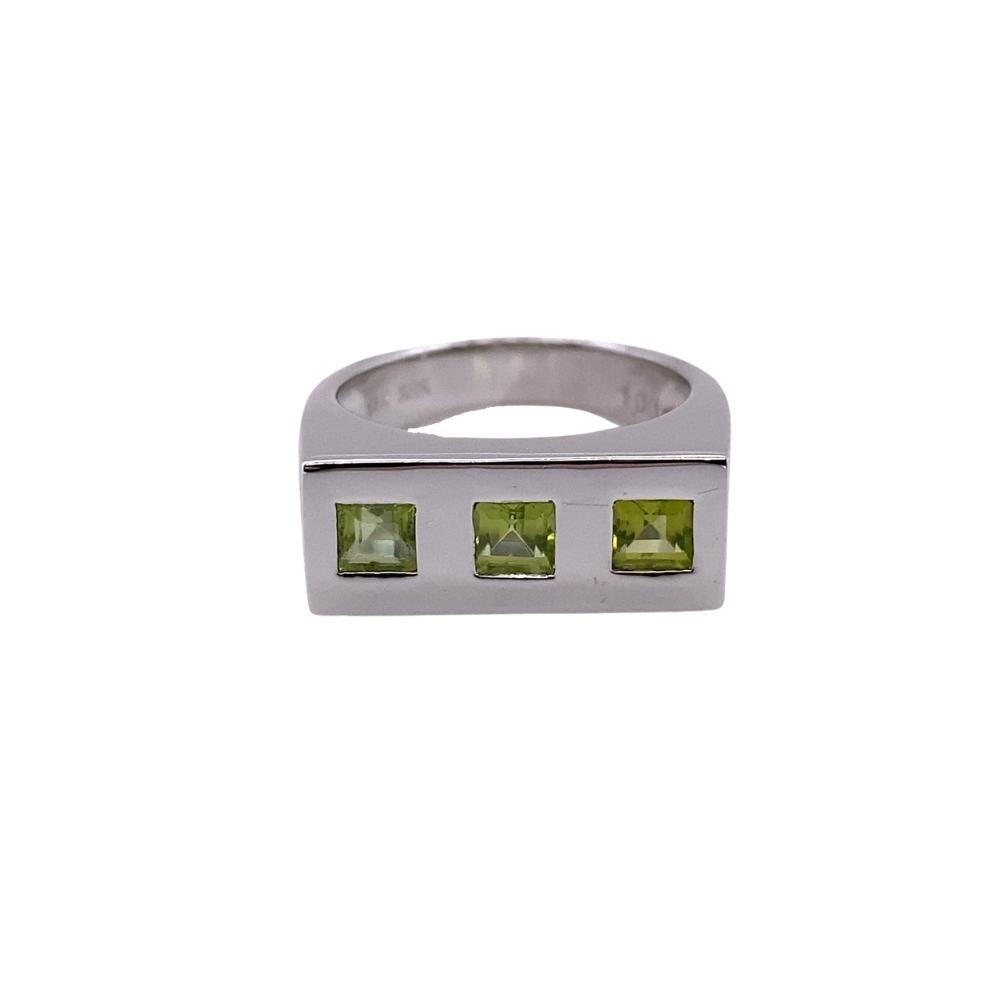 a silver ring with three green stones on it