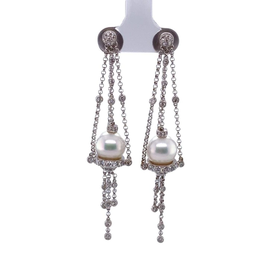 a pair of earrings with pearls hanging from chains