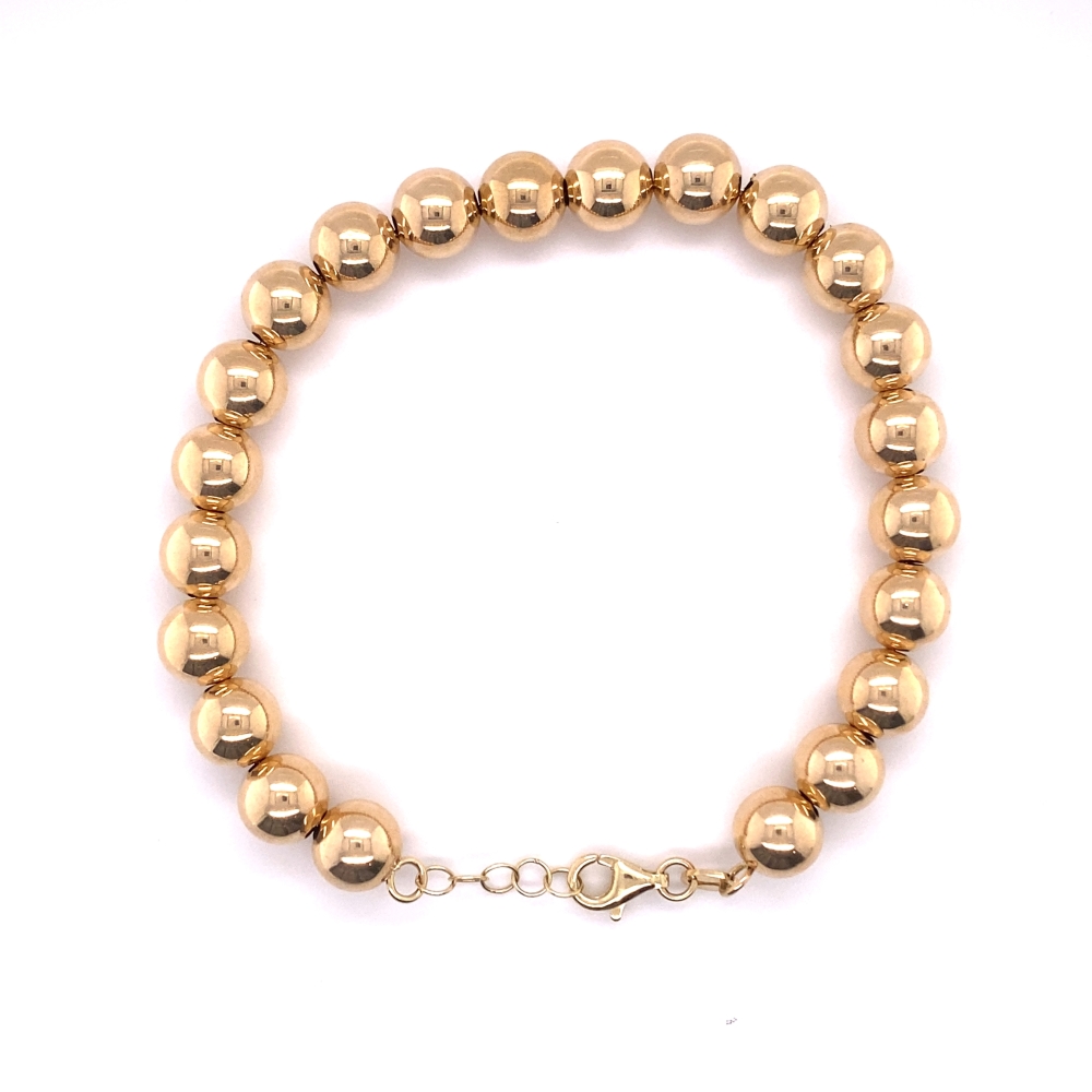 a gold beaded bracelet on a white background