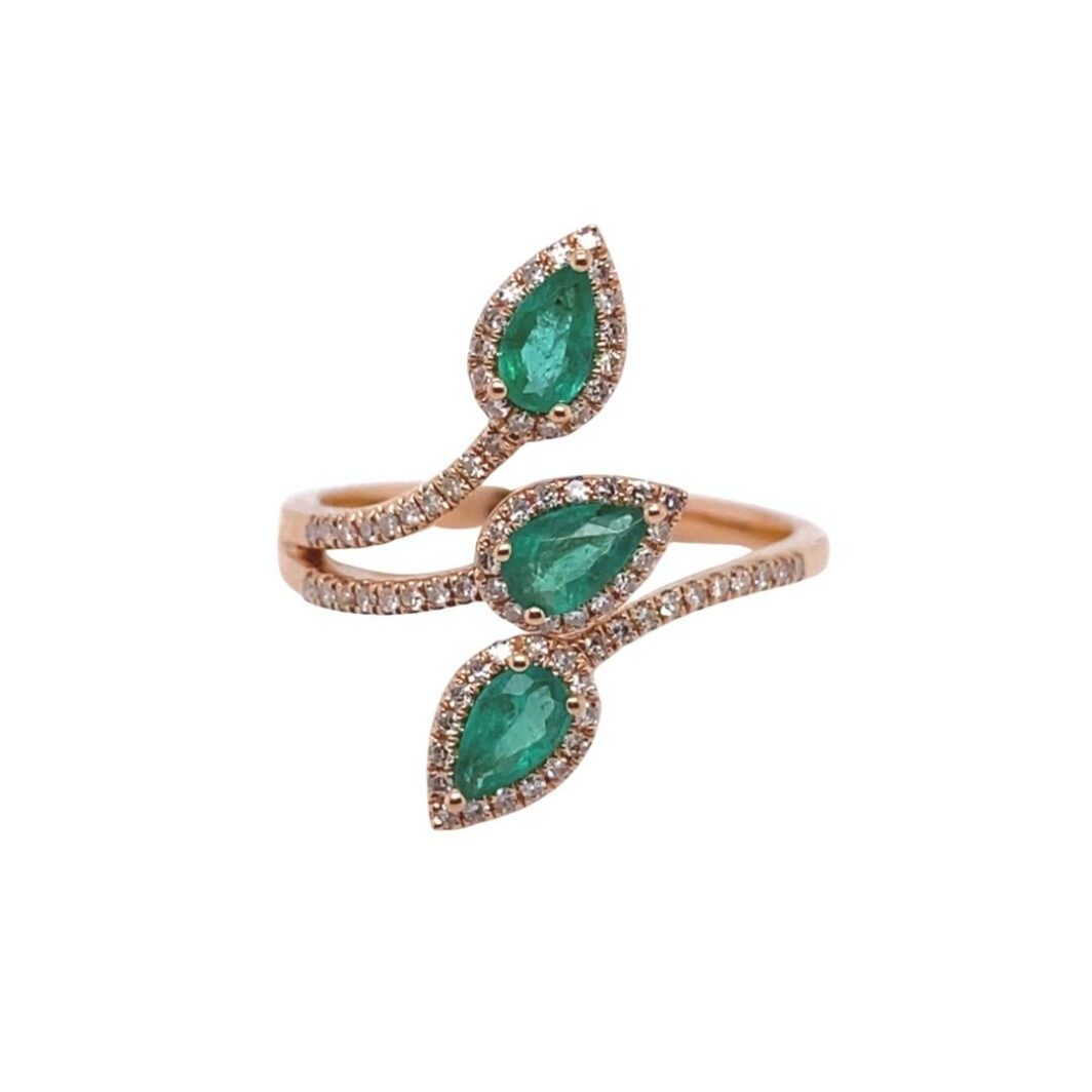 a gold ring with two pear shaped emeralds and diamonds