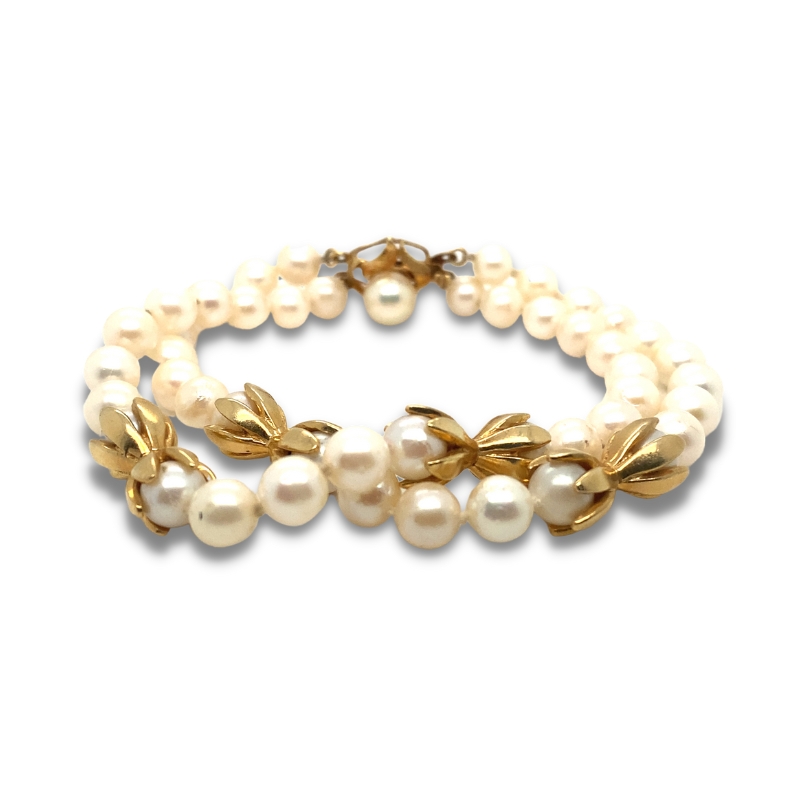 a bracelet with pearls and leaves on it