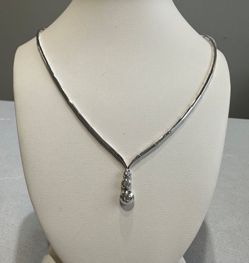 a white mannequin with a silver necklace on it