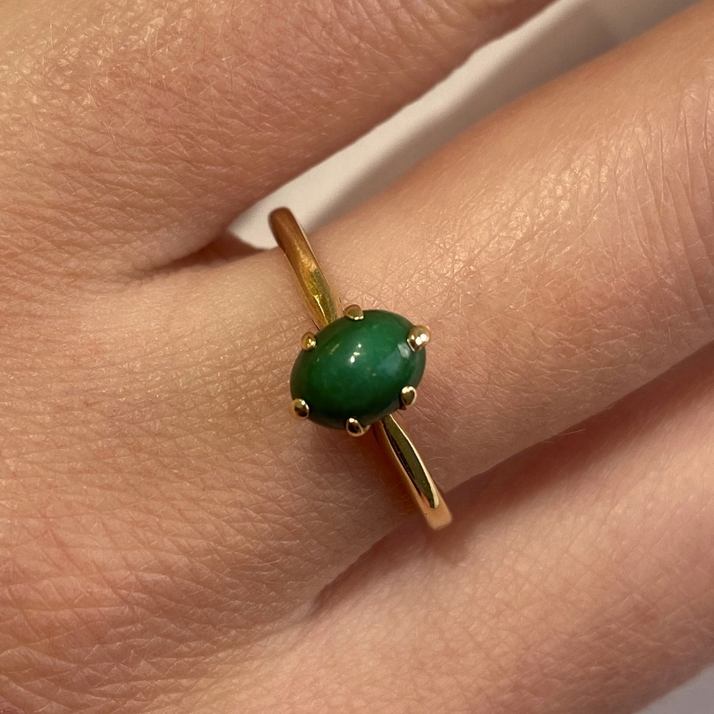 a woman's hand with a gold ring and a green stone