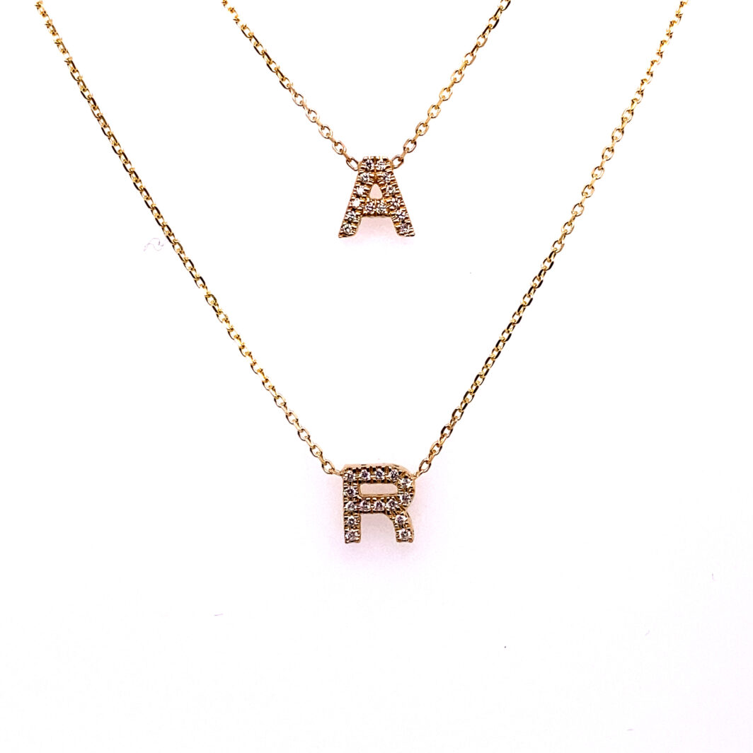 two gold necklaces with letters on them