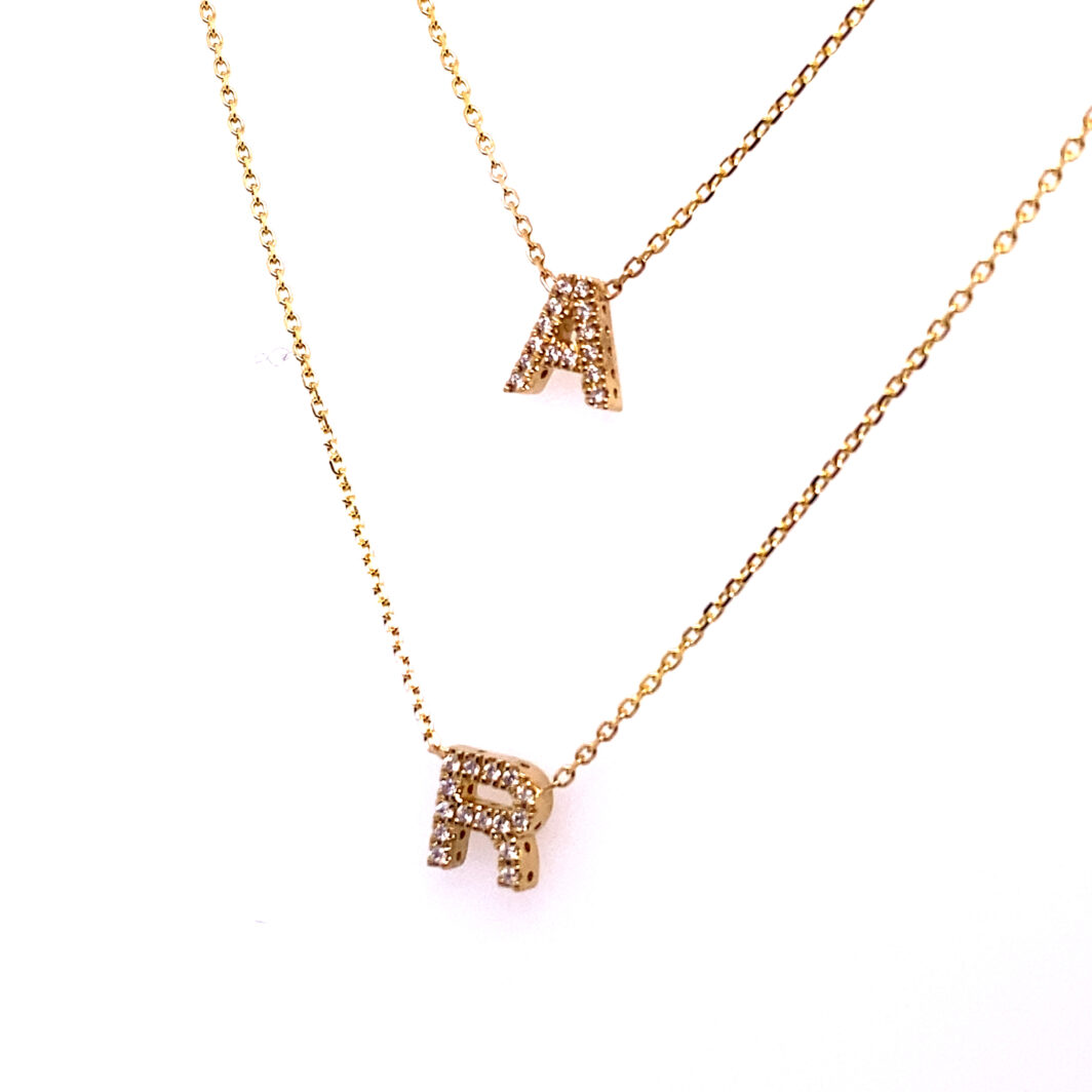 two necklaces with letters on them sitting next to each other