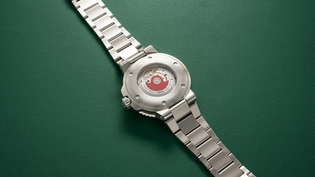 a silver watch with a red face on a green surface