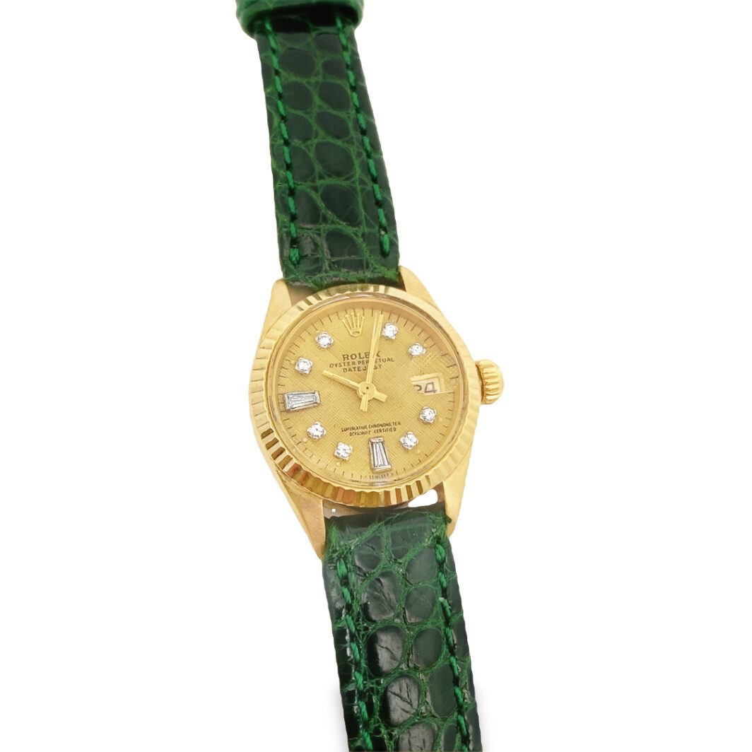 a gold watch with green leather strap