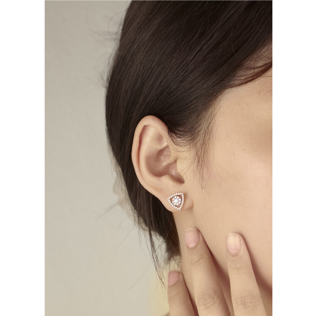a woman wearing a diamond earring with her hand on her ear
