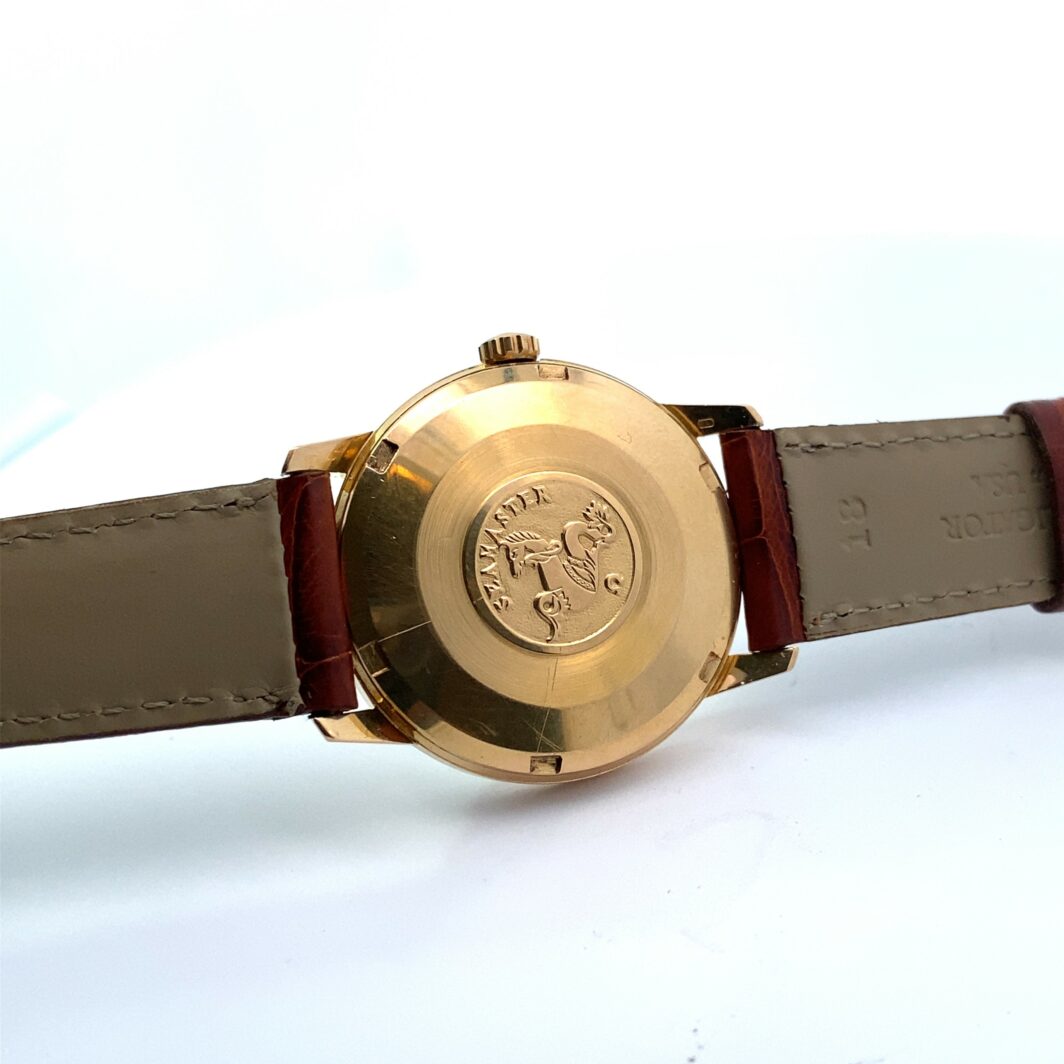 a gold watch sitting on top of a brown strap