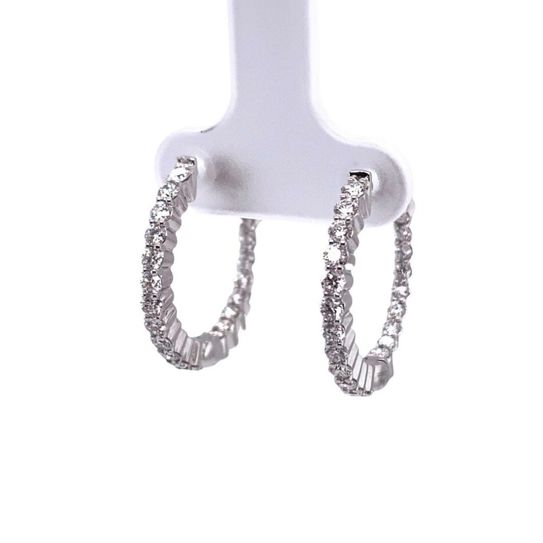 a pair of silver hoop earrings on a white stand